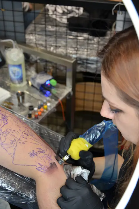 Tatuatorka wykonuje pierwsze cienie na ramieniu modela