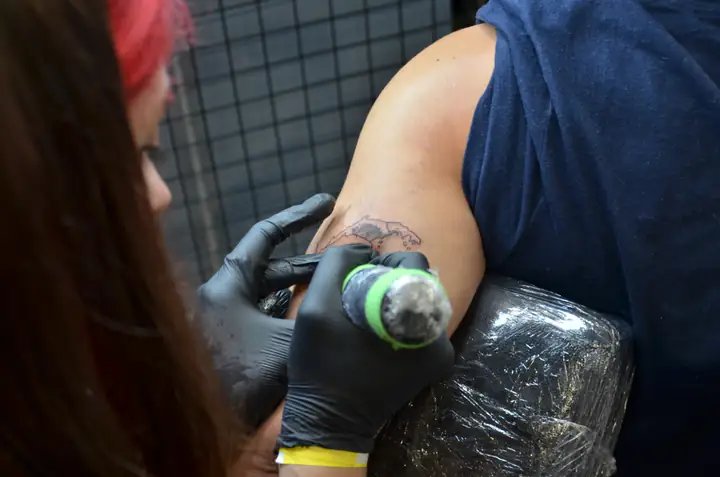 Tatuatorka wypełnia detal japońskiej fali na ramieniu