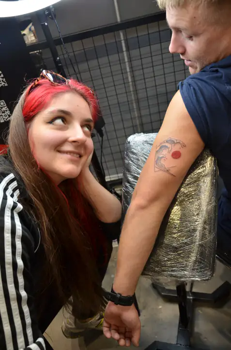 Tatuatorka i model prezentują gotowy motyw fali i słońca
